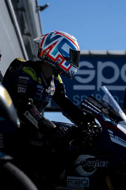 Pilota con casco sulla moto nel box